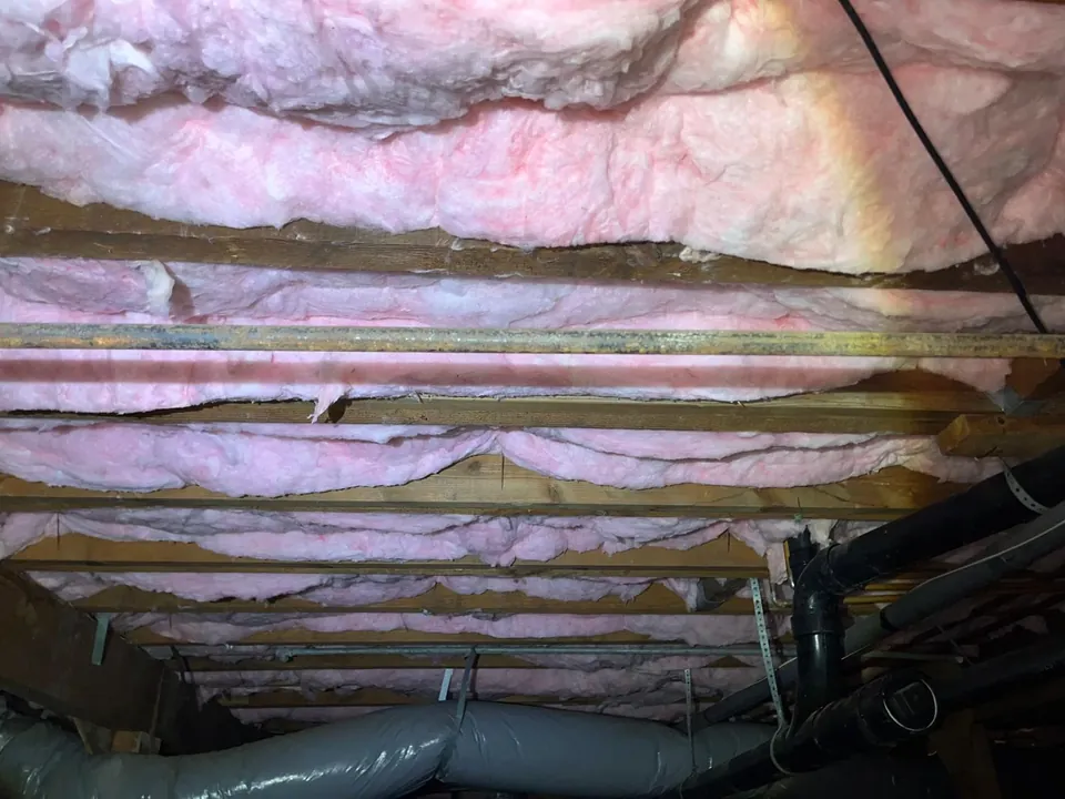 New batt insulation fitted between the floor joists in a crawl space