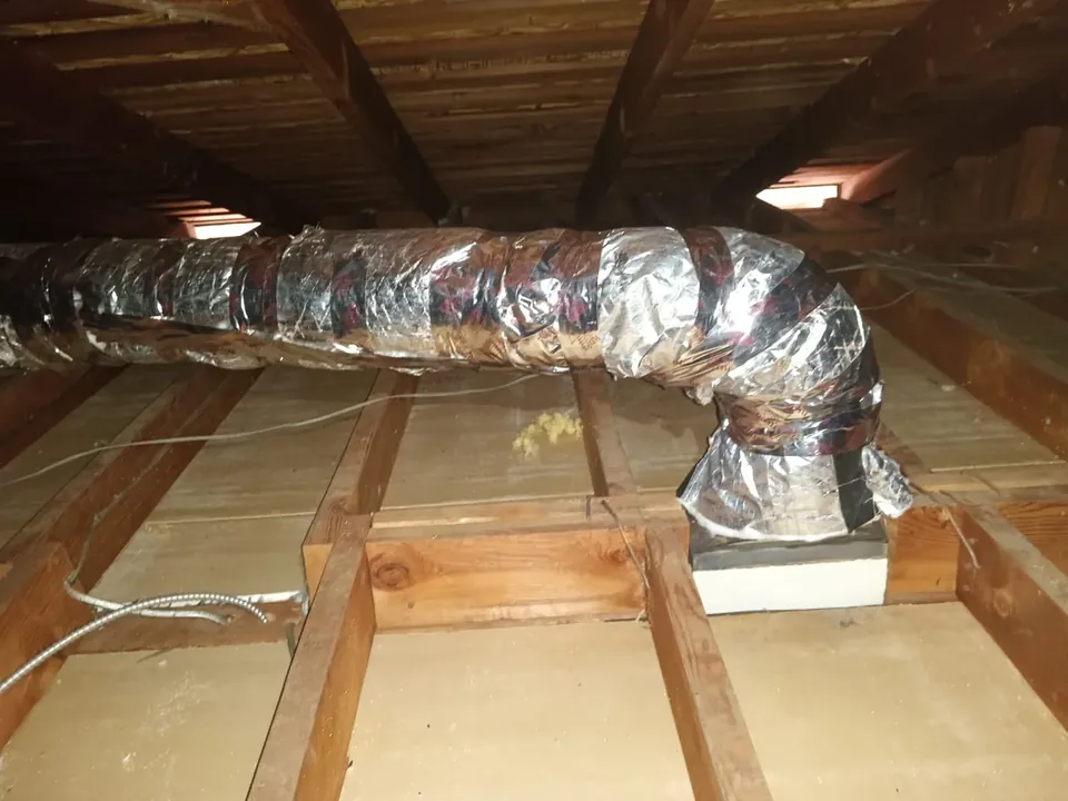New silver flexible insulated ducts run across an attic