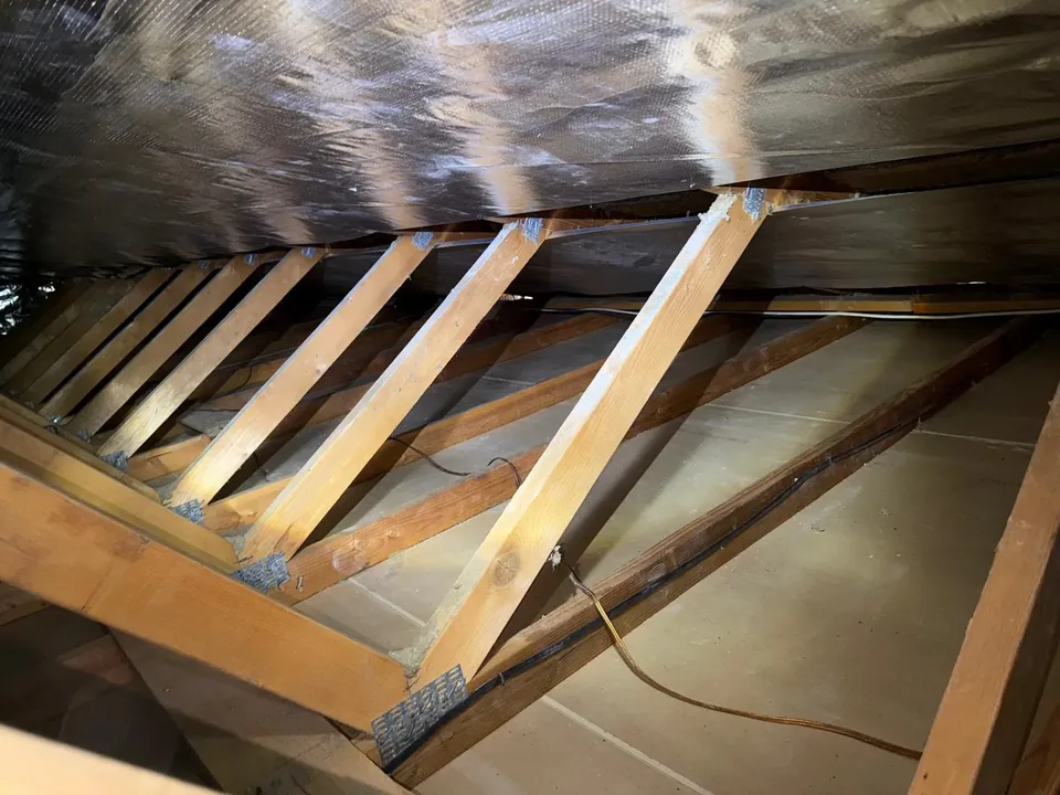 Radiant barrier foil installed along the rafters above a clean attic floor
