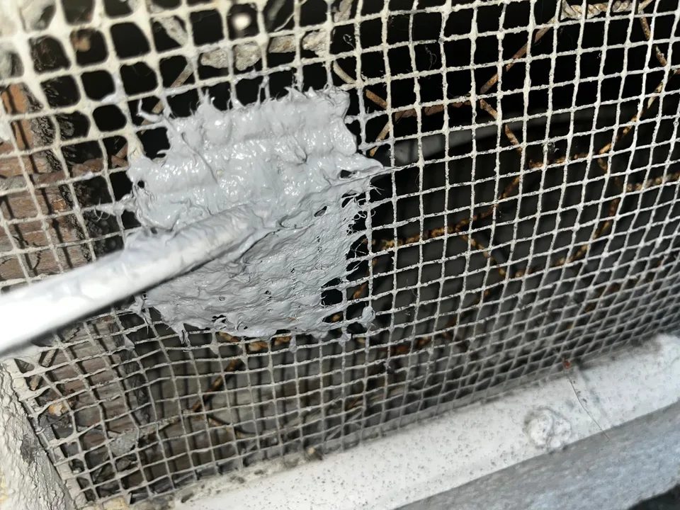 Putty over galvanized steel mesh where a pipe enters a vent