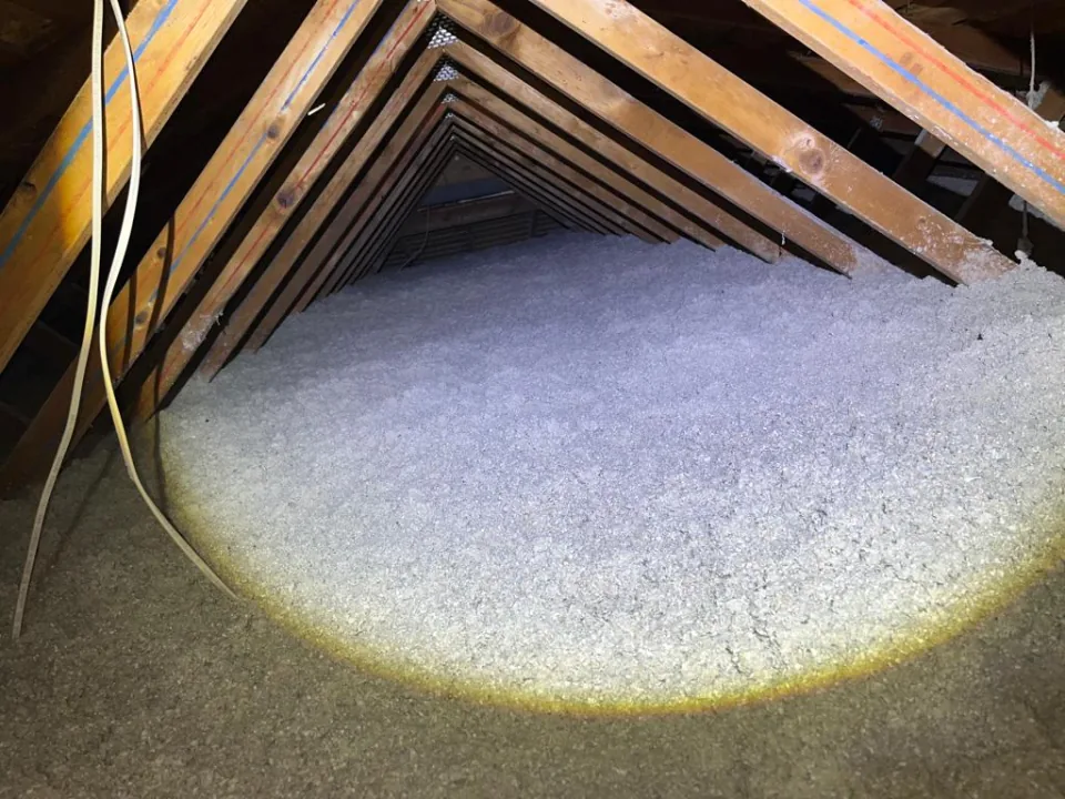 Looking down the length of the attic after the job: fresh blown-in cellulose reaching all the way to the gable end