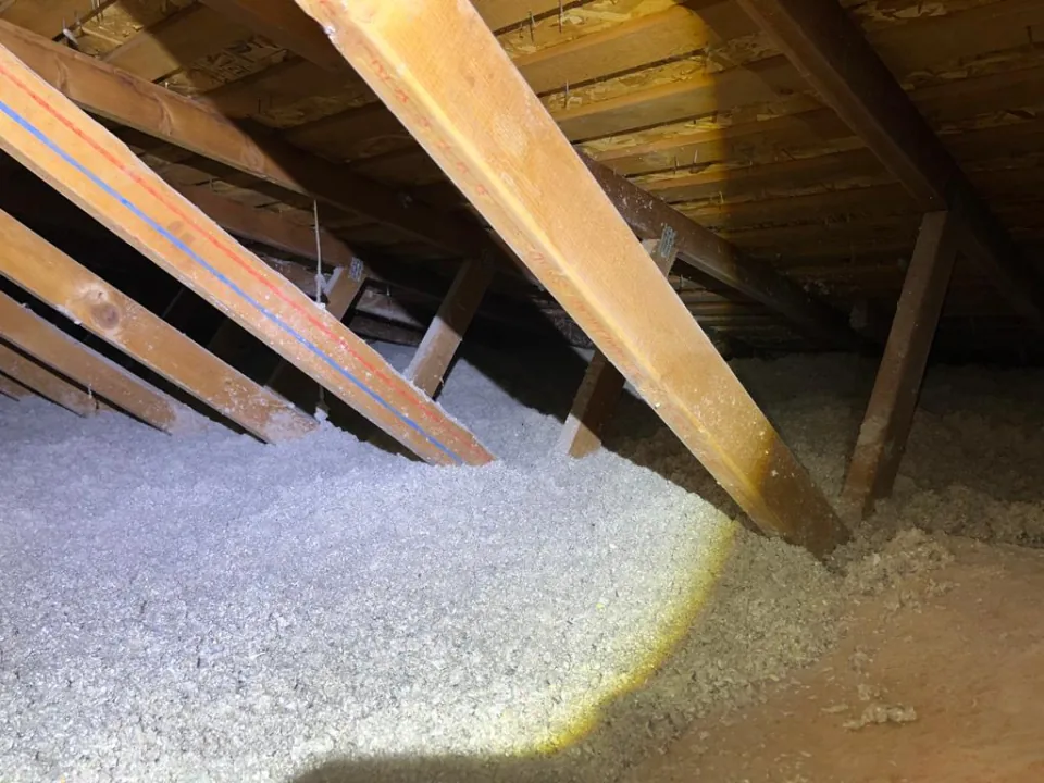 The same attic and marked trusses after the job, with an even layer of fresh blown-in cellulose across the floor